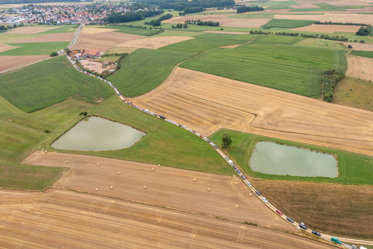 Aerial view of the Open Beatz Festival traffic queue on a rural road passing through agricultural fields and ponds near Herzogenaurach Bayern Germany. Aerial view of the Open Beatz Festival traffic queue on a rural road passing through agricultural fields and ponds near Herzogenaurach Bayern Germany.