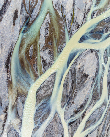 Aerial view of a glacial braided river with intricate channels of turquoise meltwater flowing through dark volcanic sediment and gravel bars in Iceland. Aerial view of a glacial braided river with intricate channels of turquoise meltwater flowing through dark volcanic sediment and gravel bars in Iceland.