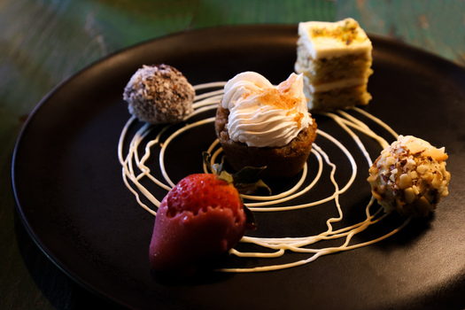 View of a gourmet dessert assortment with a small cake whipped cream strawberry and sweet treats on a black plate at Ruba s Bakery Bistro in San Jose del Cabo Baja California Sur Mexico.