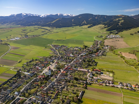 Aerial view of the village of Partizanska Lupca with its church tower surrounded by green fields and the snow capped Tatra Mountains in Partizanska Lupca Zilina Region Slovakia.