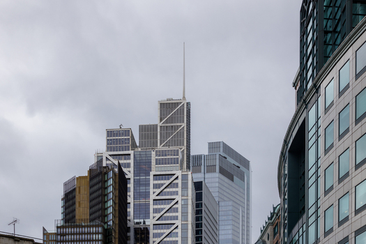 View of modern skyscrapers in the City of London featuring the distinctive spire of the Heron Tower against a cloudy sky in London England United Kingdom.