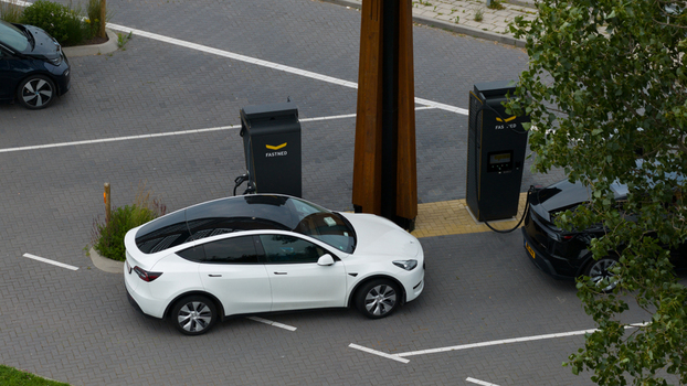 Krabbendijke Netherlands 28 June 2026 Aerial view of a Fastned electric vehicle charging station with a white Tesla Model Y and another electric car parked and charging on a paved lot. Krabbendijke Netherlands 28 June 2026 Aerial view of a Fastned electric vehicle charging station with a white Tesla Model Y and another electric car parked and charging on a paved lot.