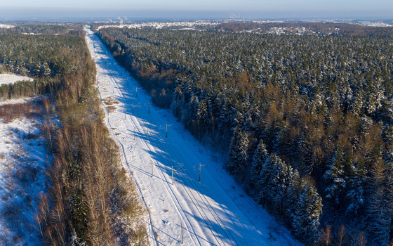 Aerial view of snow covered railway tracks passing through a dense pine forest under a clear winter sky Lithuania. Aerial view of snow covered railway tracks passing through a dense pine forest under a clear winter sky Lithuania.
