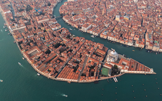 Aerial view of the historic city of Venice featuring the Santa Maria della Salute basilica and Punta della Dogana surrounded by the Grand Canal and Venetian Lagoon. Venice Veneto Italy. Aerial view of the historic city of Venice featuring the Santa Maria della Salute basilica and Punta della Dogana surrounded by the Grand Canal and Venetian Lagoon. Venice Veneto Italy.