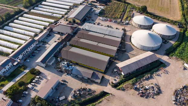 Aerial view of an agricultural complex featuring rows of greenhouses large storage silos and farm buildings surrounded by fields in Milan Lombardy Italy. Aerial view of an agricultural complex featuring rows of greenhouses large storage silos and farm buildings surrounded by fields in Milan Lombardy Italy.