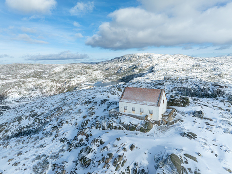 Aerial view of a solitary white building with a red roof amidst a snow dusted rocky landscape under a cloudy sky Lagoa Comprida São Romão Serra da Estrella Portugal. Aerial view of a solitary white building with a red roof amidst a snow dusted rocky landscape under a cloudy sky Lagoa Comprida São Romão Serra da Estrella Portugal.