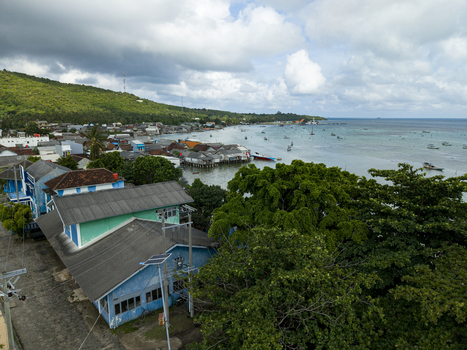 Aerial view of the coastal town meeting the turquoise sea under a sky brushed with grey and white Karimunjawa Central Java Indonesia. Aerial view of the coastal town meeting the turquoise sea under a sky brushed with grey and white Karimunjawa Central Java Indonesia.