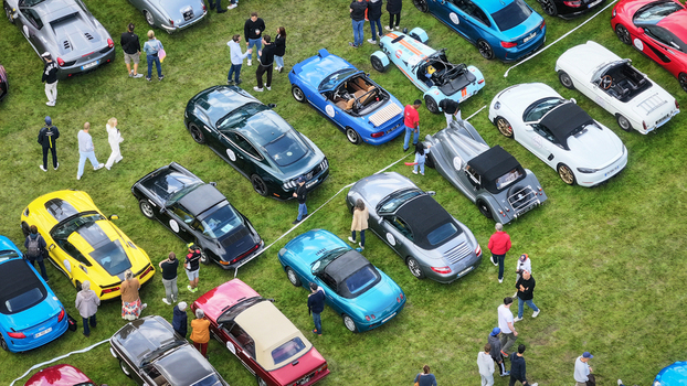 La Chapelle de Guinchay France 01 June 2024 Aerial view of a collection of classic and modern sports cars parked on a green lawn during an outdoor automotive event with people.