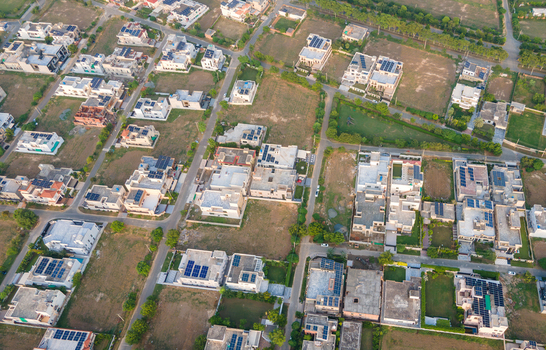 Aerial view of a modern residential neighborhood featuring houses equipped with solar panels on their rooftops in Lahore Punjab Pakistan.