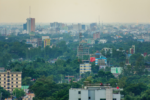Aerial view of the urban landscape of Bogura featuring a mix of mid rise buildings and dense green trees under a hazy sky in Bogura Rajshahi Division Bangladesh. Aerial view of the urban landscape of Bogura featuring a mix of mid rise buildings and dense green trees under a hazy sky in Bogura Rajshahi Division Bangladesh.