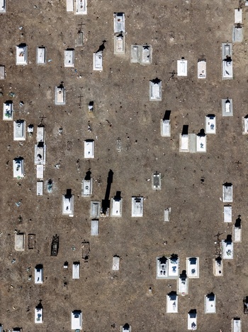 Aerial view of a cemetery with white gravestones casting long shadows on dry ground in Evora Evora District Portugal. Aerial view of a cemetery with white gravestones casting long shadows on dry ground in Evora Evora District Portugal.