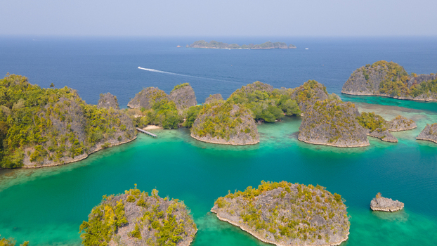 Aerial view of Piaynemo karst islands surrounded by turquoise waters and lush tropical vegetation in Raja Ampat Papua Barat Indonesia. Aerial view of Piaynemo karst islands surrounded by turquoise waters and lush tropical vegetation in Raja Ampat Papua Barat Indonesia.