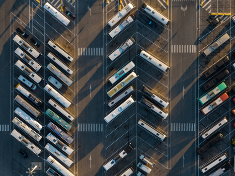 Aerial view of rows of parked buses at the Civitavecchia Port automotive terminal with long shadows cast across the asphalt in Civitavecchia Lazio Italy. Aerial view of rows of parked buses at the Civitavecchia Port automotive terminal with long shadows cast across the asphalt in Civitavecchia Lazio Italy.