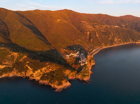 Aerial view of the historic village of Corniglia perched on a cliffside surrounded by lush green hills and the calm sea at sunset Corniglia Liguria Italy. Aerial view of the historic village of Corniglia perched on a cliffside surrounded by lush green hills and the calm sea at sunset Corniglia Liguria Italy.