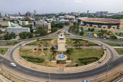 Aerial view of the iconic Independence Arch rising from the roundabout contrasting with the modern cityscape and the stadium in the distance Accra Ghana. Aerial view of the iconic Independence Arch rising from the roundabout contrasting with the modern cityscape and the stadium in the distance Accra Ghana.