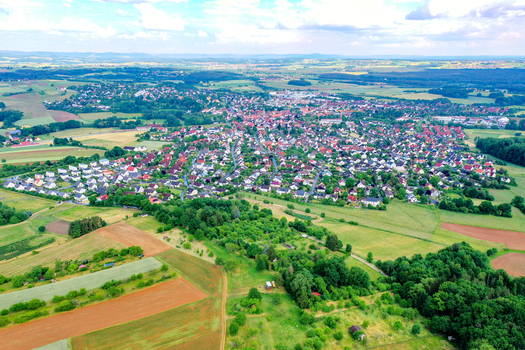 Aerial view of the town of Neunkirchen am Brand featuring traditional red roofed houses surrounded by vibrant green fields and rolling hills in Neunkirchen am Brand Bavaria Germany. Aerial view of the town of Neunkirchen am Brand featuring traditional red roofed houses surrounded by vibrant green fields and rolling hills in Neunkirchen am Brand Bavaria Germany.