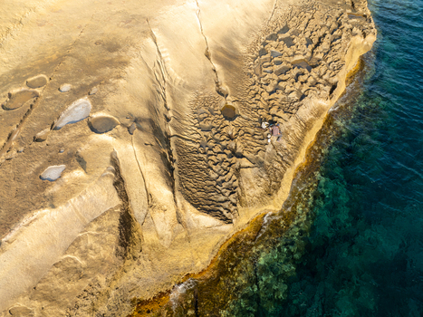 Aerial view of the rugged sun baked coastline meets the turquoise sea in a stunning display of natural beauty Gozo Malta. Aerial view of the rugged sun baked coastline meets the turquoise sea in a stunning display of natural beauty Gozo Malta.