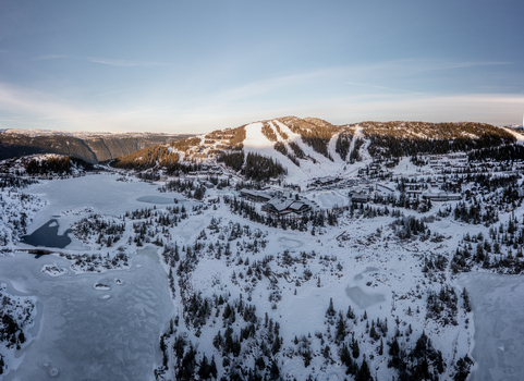 Aerial view of Gaustablikk Fjellresort surrounded by snow covered mountains ski slopes and a frozen lake in Rjukan Telemark Norway. Aerial view of Gaustablikk Fjellresort surrounded by snow covered mountains ski slopes and a frozen lake in Rjukan Telemark Norway.