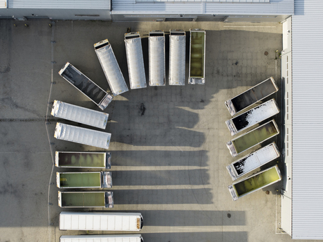Aerial view of a fleet of semi trailers parked in a semi circular formation on an asphalt lot next to a warehouse building in Krakow Lesser Poland Voivode Poland. Aerial view of a fleet of semi trailers parked in a semi circular formation on an asphalt lot next to a warehouse building in Krakow Lesser Poland Voivode Poland.