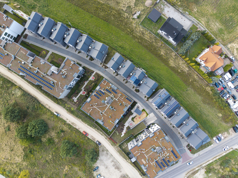 Aerial view of a modern residential neighborhood featuring rows of houses with flat roofs solar panels and green surroundings in Poland. Aerial view of a modern residential neighborhood featuring rows of houses with flat roofs solar panels and green surroundings in Poland.