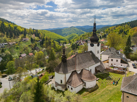 Aerial view of the historic Church of the Conversion of the Lord surrounded by traditional houses and lush green hills Spania Dolina Banska Bystrica Regio Slovakia.