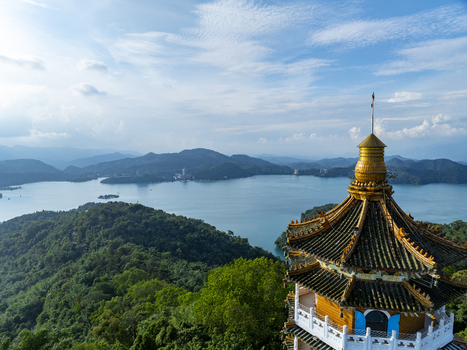 Aerial view of the Ci en Pagoda overlooking the serene waters of Sun Moon Lake surrounded by lush green hills under a bright blue sky in Yuchi Township Nantou County Taiwan. Aerial view of the Ci en Pagoda overlooking the serene waters of Sun Moon Lake surrounded by lush green hills under a bright blue sky in Yuchi Township Nantou County Taiwan.