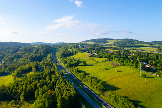 Aerial view of the D10 highway winding through lush green hills and forests in Liberec Liberec Region Czechia.