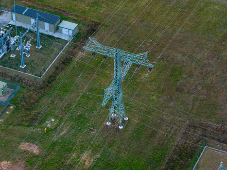Aerial view of a high voltage transmission tower standing in a grassy field near a power substation in Jacobsdorf Brandenburg Germany. Aerial view of a high voltage transmission tower standing in a grassy field near a power substation in Jacobsdorf Brandenburg Germany.