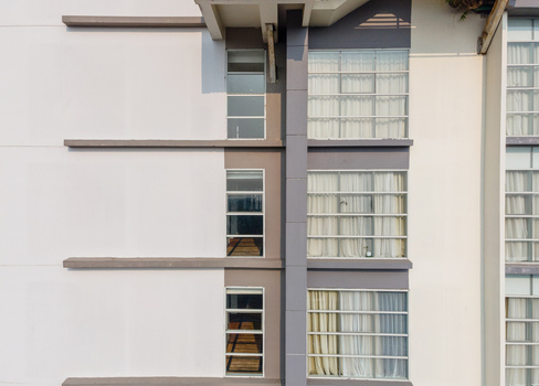 Aerial view of a modern building facade featuring clean white and grey walls large windows with white curtains and horizontal architectural lines in Purwokerto Central Java Indonesia. Aerial view of a modern building facade featuring clean white and grey walls large windows with white curtains and horizontal architectural lines in Purwokerto Central Java Indonesia.
