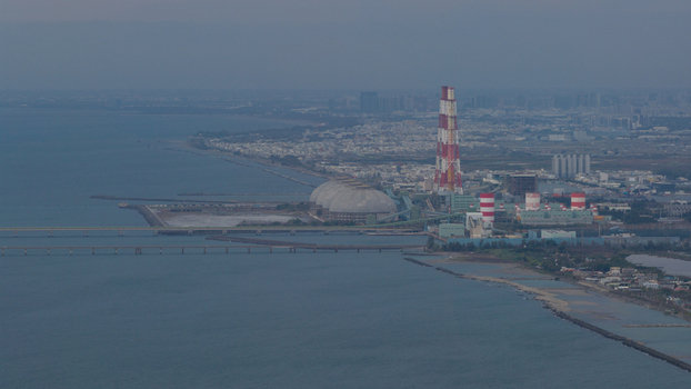 Aerial view of Hsinta Power Plant featuring its tall red and white striped chimney and large storage domes along the coast in Xingang Village Kaohsiung City Taiwan.