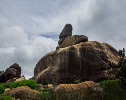 View of the prominent rock formation in the Jos Plateau region featuring large granite boulders lush green vegetation and cacti under a cloudy sky in Jos Plateau Nigeria. View of the prominent rock formation in the Jos Plateau region featuring large granite boulders lush green vegetation and cacti under a cloudy sky in Jos Plateau Nigeria.