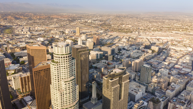 Aerial view of the Los Angeles skyline featuring modern skyscrapers dense urban architecture and city streets under a warm golden hour light in Los Angeles California United States.
