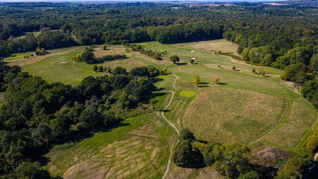 Aerial view of Hamptworth Golf course featuring lush green fairways sand bunkers and a winding dirt path surrounded by dense forest in Hamptworth England United Kingdom. Aerial view of Hamptworth Golf course featuring lush green fairways sand bunkers and a winding dirt path surrounded by dense forest in Hamptworth England United Kingdom.
