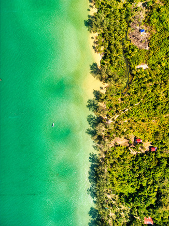 Aerial view of the vibrant turquoise waters meeting the lush green coastline a tropical paradise bathed in sunlight Preah Sihanouk Sihanoukville Cambodia.