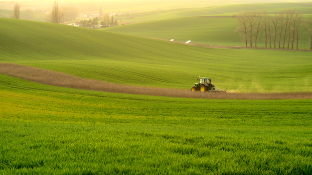 View of a tractor working in a field amidst the rolling green hills of Moravia in Brno City District South Moravian Region Czechia.
