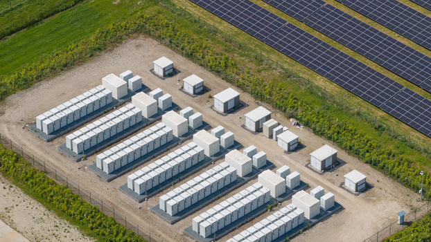Aerial view of a battery energy storage system facility with rows of white containers adjacent to a large solar panel array in Wanneperveen Overijssel Netherlands.