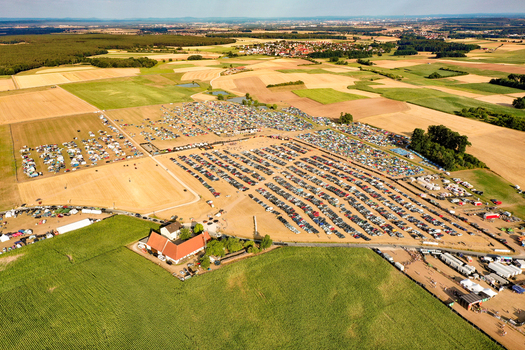 Herzogenaurach Germany 22 July 2022 Aerial view of Open Beatz Festival with thousands of tents and parked cars spread across rural fields under a clear sky. Herzogenaurach Germany 22 July 2022 Aerial view of Open Beatz Festival with thousands of tents and parked cars spread across rural fields under a clear sky.