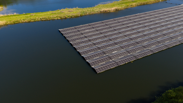 Aerial view of a large array of floating solar panels on a calm lake surface near a green grassy bank in Zwolle Overijssel Netherlands. Aerial view of a large array of floating solar panels on a calm lake surface near a green grassy bank in Zwolle Overijssel Netherlands.