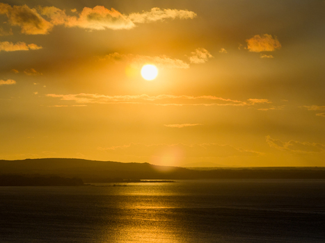Aerial view of a golden sunset over the ocean with silhouetted hills and clouds at Torndirrup National Park in Torndirrup Western Australia Australia.