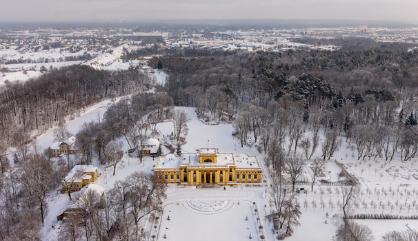 Aerial view of the yellow neoclassical Traku Voke Manor surrounded by snow covered parkland and bare winter trees in Vilnius Vilniaus apskritis Lithuania.