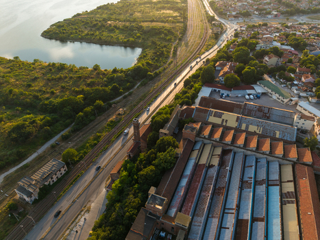 Aerial view of the industrial factory complex with a tall brick chimney situated next to a road railway tracks and the scenic Varna Lake in Varna Varna Bulgaria. Aerial view of the industrial factory complex with a tall brick chimney situated next to a road railway tracks and the scenic Varna Lake in Varna Varna Bulgaria.
