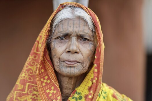 Odisha India 26 March 2026 View of an elderly woman s face adorned with traditional tattoos framed by a vibrant orange and yellow patterned headscarf. Odisha India 26 March 2026 View of an elderly woman s face adorned with traditional tattoos framed by a vibrant orange and yellow patterned headscarf.