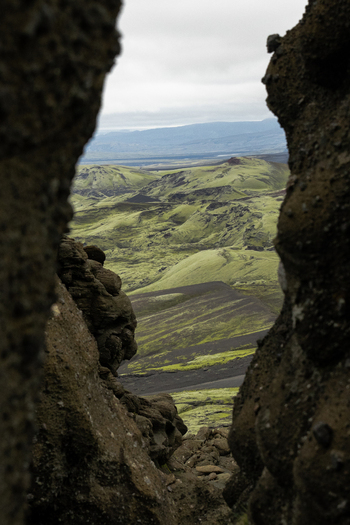 View of a green and black landscape seen through a narrow rocky gap the sky a pale grey above Skaftárhreppur Skaftárhreppur Iceland. View of a green and black landscape seen through a narrow rocky gap the sky a pale grey above Skaftárhreppur Skaftárhreppur Iceland.