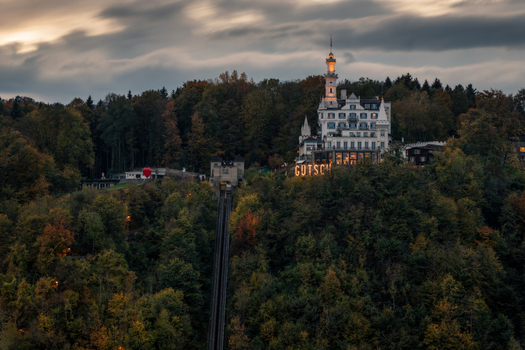 View of the illuminated Chateau Gutsch hotel and funicular railway track surrounded by autumn forest at dusk Lucerne Lucerne Switzerland. View of the illuminated Chateau Gutsch hotel and funicular railway track surrounded by autumn forest at dusk Lucerne Lucerne Switzerland.