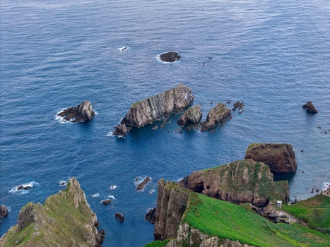 Aerial view of Silence Beach Viewpoint with jagged sea stacks steep green cliffs and deep blue waters of the Cantabrian Sea in Cudillero Asturias Spain.