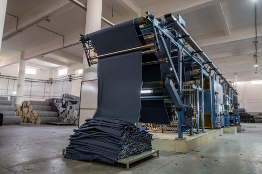 View of a denim factory production line with fabric being processed through industrial machinery and stacked in a textile manufacturing facility in Karachi Sindh Pakistan. View of a denim factory production line with fabric being processed through industrial machinery and stacked in a textile manufacturing facility in Karachi Sindh Pakistan.