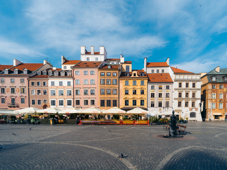 View of the colorful historic buildings and outdoor restaurant seating in the Warsaw Old Town square under a clear blue sky in Warsaw Masovian Voivodeship Poland. View of the colorful historic buildings and outdoor restaurant seating in the Warsaw Old Town square under a clear blue sky in Warsaw Masovian Voivodeship Poland.