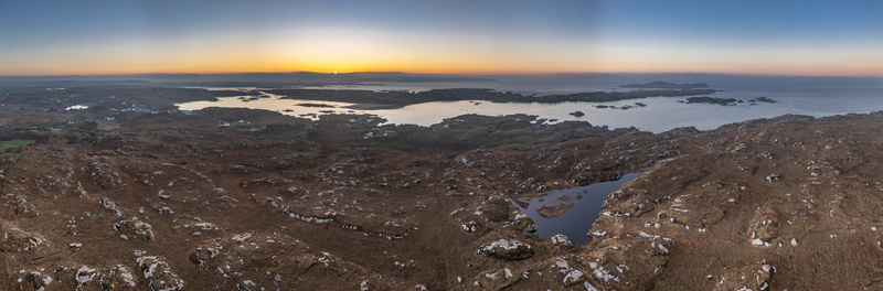 Aerial view of the rugged coastal landscape of Kincasslagh at sunset featuring rocky terrain small lakes and the Atlantic Ocean Kincasslagh County Donegal Ireland. Aerial view of the rugged coastal landscape of Kincasslagh at sunset featuring rocky terrain small lakes and the Atlantic Ocean Kincasslagh County Donegal Ireland.