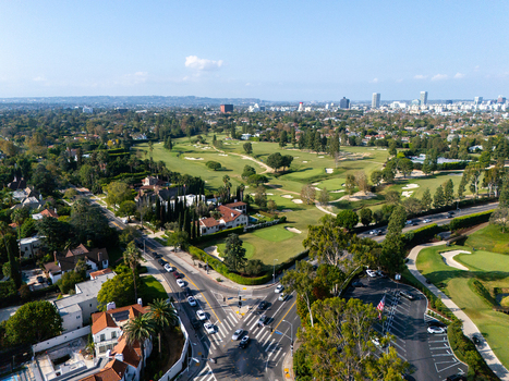 Aerial view of Wilshire Country Club featuring lush green fairways and sand bunkers surrounded by residential homes and the urban skyline of Los Angeles California United States. Aerial view of Wilshire Country Club featuring lush green fairways and sand bunkers surrounded by residential homes and the urban skyline of Los Angeles California United States.