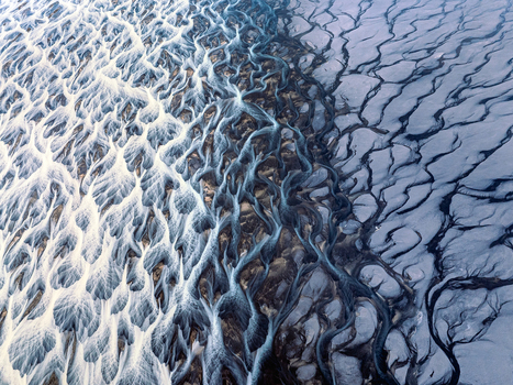 Aerial view of a complex braided river system with dark volcanic sediment and intricate water channels in Iceland. Aerial view of a complex braided river system with dark volcanic sediment and intricate water channels in Iceland.